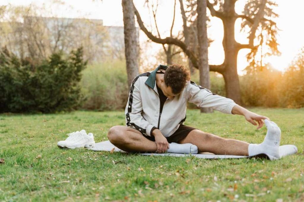 Man stretching outdoors on a yoga mat in a park, highlighting the importance of physical activity for maintaining hormonal balance and overall men’s health.