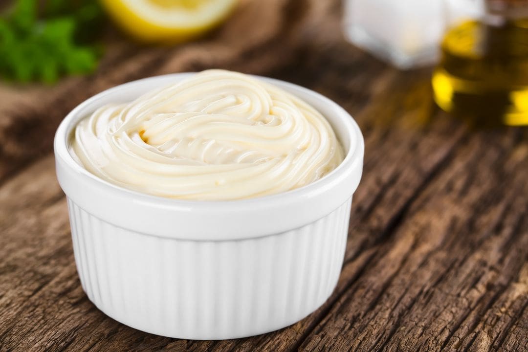 Copycat Miracle Whip recipe featuring a creamy and tangy spread made with avocado oil, presented in a white ramekin on a rustic wooden surface.