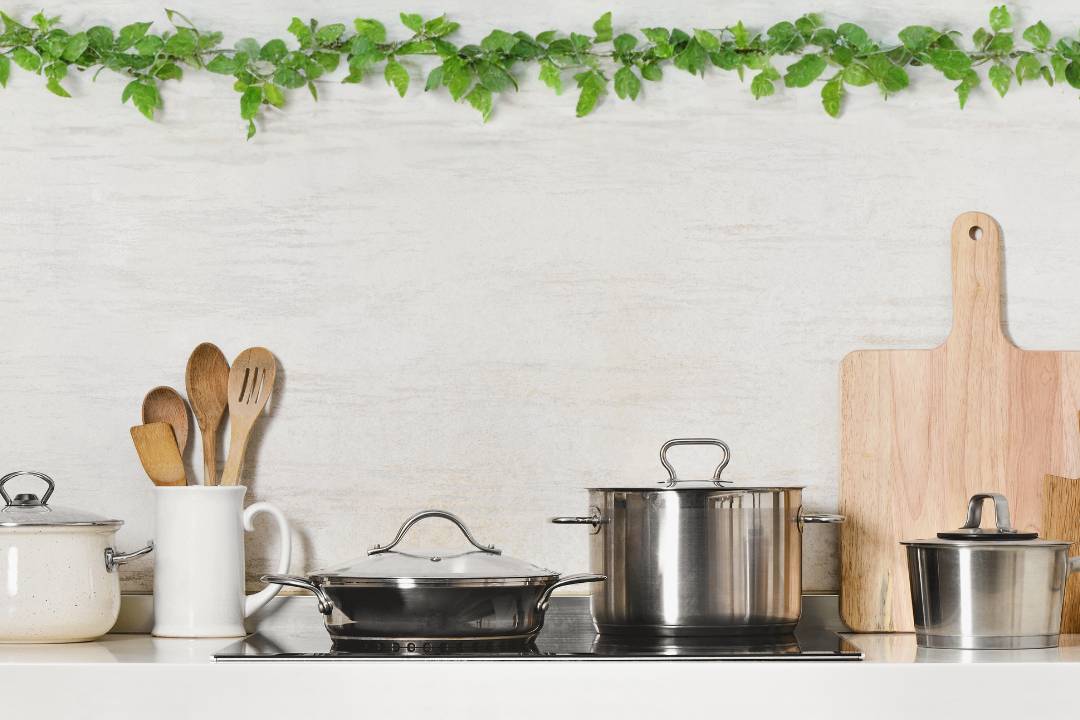 Non-toxic kitchen essentials including stainless steel pots, wooden utensils, and cutting boards on a clean countertop, representing healthier cooking tools for a safer home.