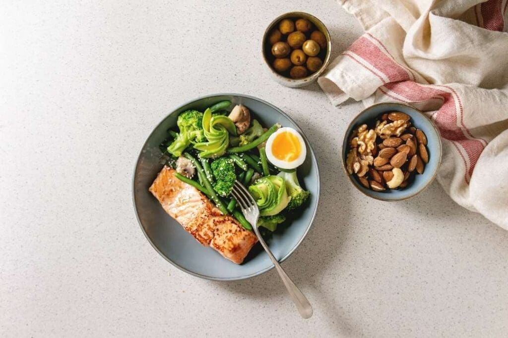 Nutrient-dense meal with salmon, broccoli, avocado, soft-boiled egg, and nuts, supporting a 12-14 hour fasting window for optimal health and digestion.